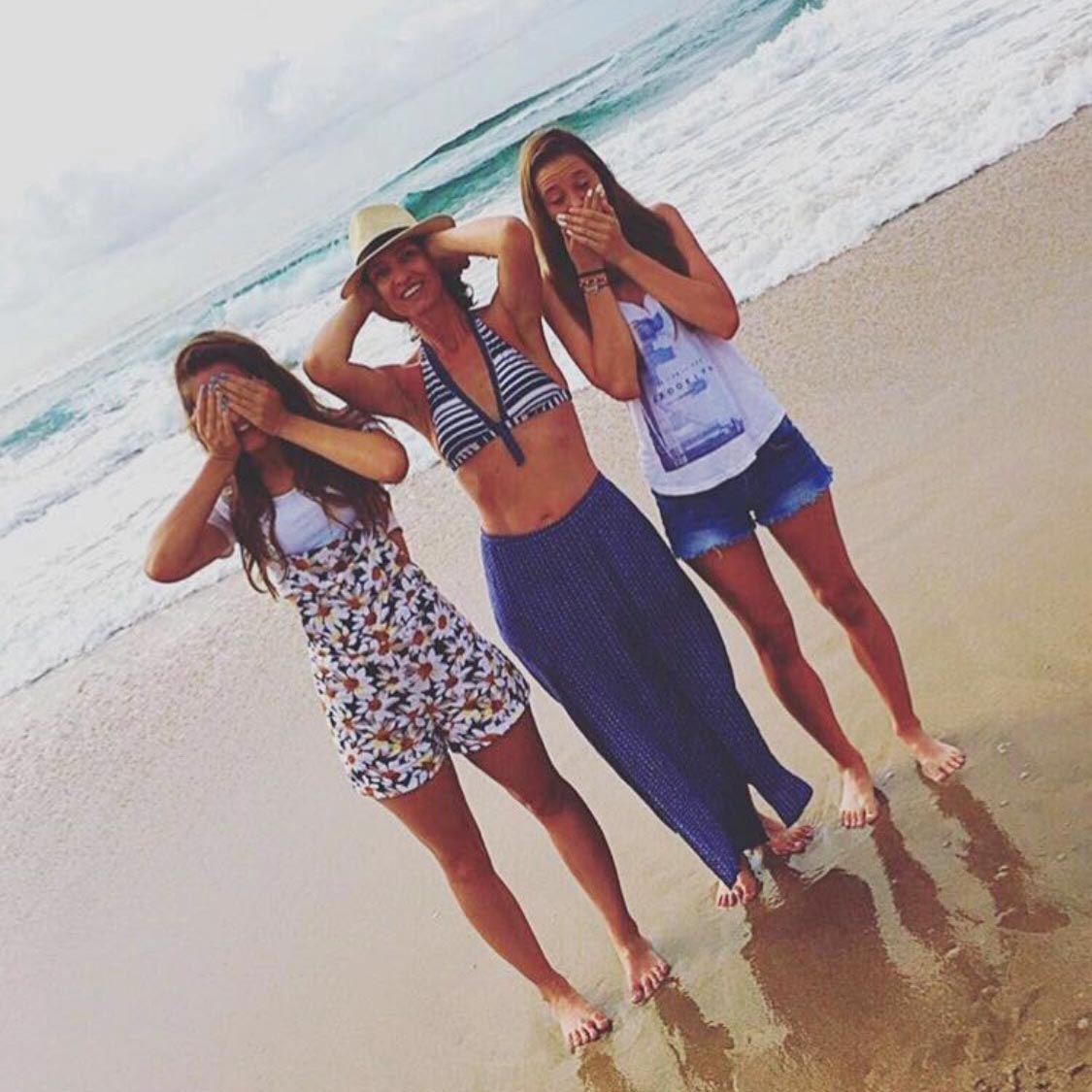 Drei Mädchen bilden am Strand die Posen der Drei Affen nach