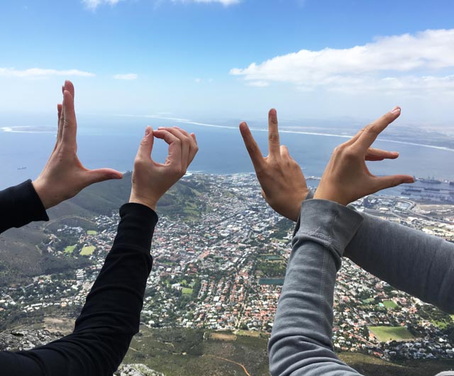 Zwei Schüler formen mit ihren Händen das Wort Love vor einem Stadtpanorama
